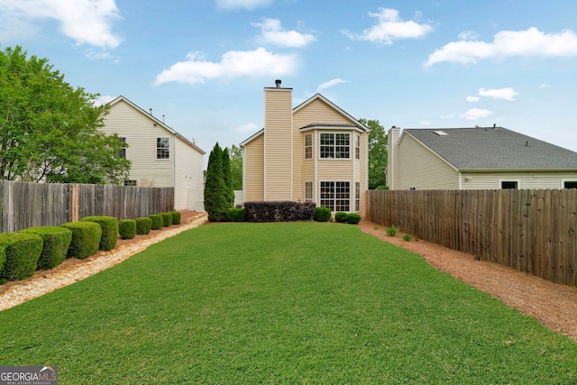 back of property featuring a yard, a fenced backyard, and a chimney