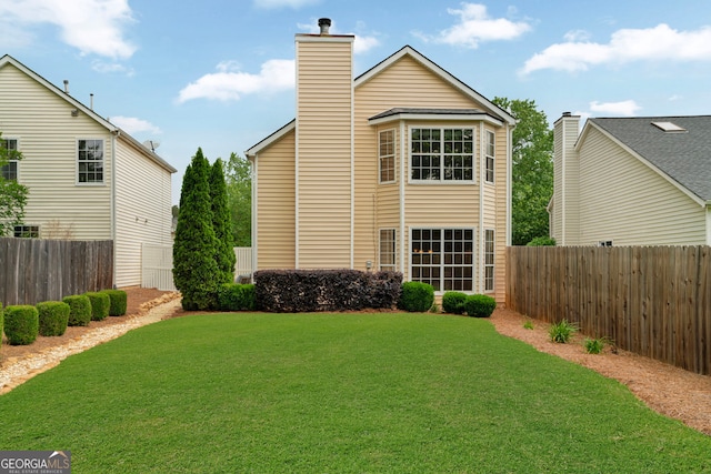 rear view of property featuring fence private yard, a chimney, and a lawn