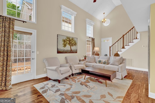 living room with stairs, baseboards, high vaulted ceiling, and wood finished floors