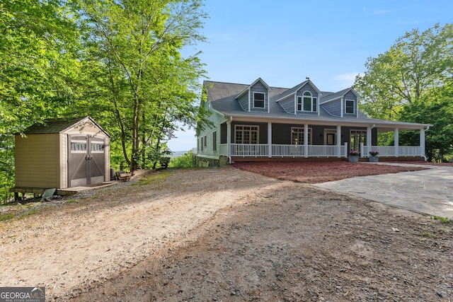 view of front facade featuring a porch, driveway, an outbuilding, and a shed