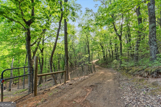 view of road with a gate and a wooded view