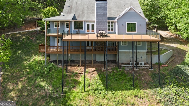 rear view of property featuring a chimney, roof with shingles, and a deck