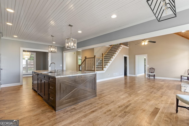 kitchen with crown molding, dark brown cabinets, a sink, open floor plan, and stainless steel dishwasher
