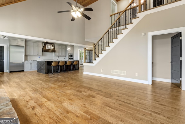 unfurnished living room with a ceiling fan, high vaulted ceiling, visible vents, and light wood-style floors