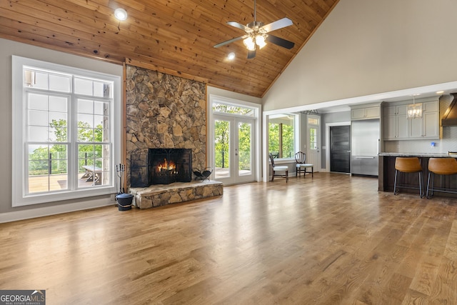 living area featuring high vaulted ceiling, wood finished floors, a healthy amount of sunlight, and a fireplace
