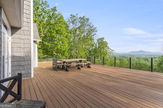 wooden deck with a mountain view and outdoor dining space