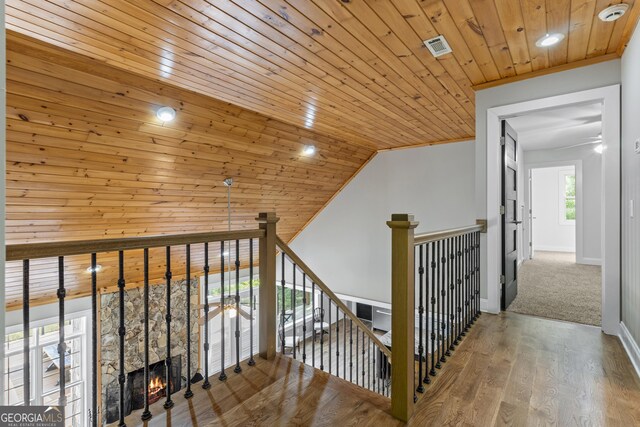 hall with baseboards, an upstairs landing, wood finished floors, and wooden ceiling
