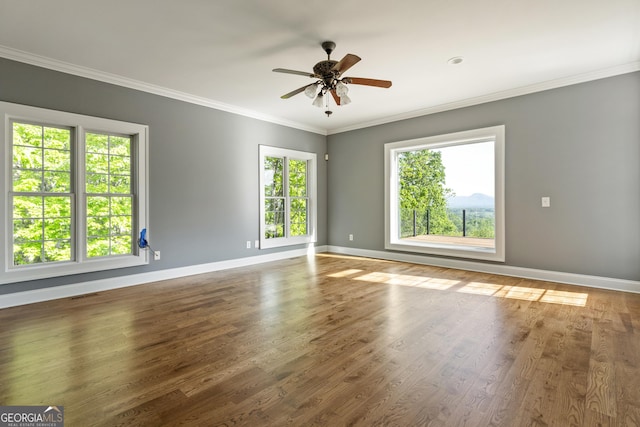 spare room featuring crown molding, baseboards, a ceiling fan, and wood finished floors
