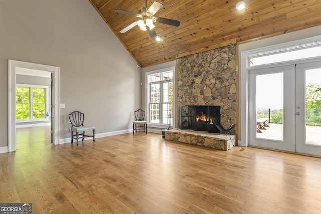 unfurnished living room featuring high vaulted ceiling, a stone fireplace, a ceiling fan, baseboards, and wooden ceiling