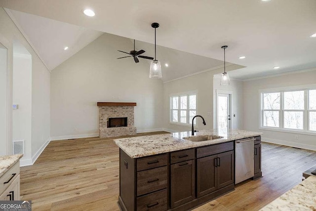 kitchen with ceiling fan, visible vents, stainless steel dishwasher, a brick fireplace, and a sink