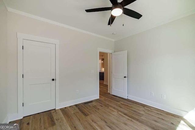 unfurnished bedroom featuring crown molding, baseboards, a ceiling fan, and wood finished floors