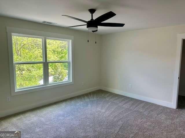 carpeted empty room featuring plenty of natural light, a ceiling fan, and baseboards