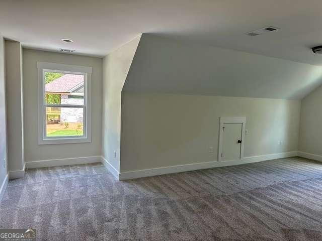 additional living space with carpet floors, baseboards, lofted ceiling, and visible vents