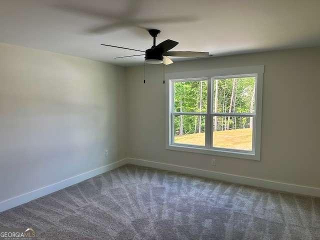 spare room featuring carpet floors, baseboards, and ceiling fan