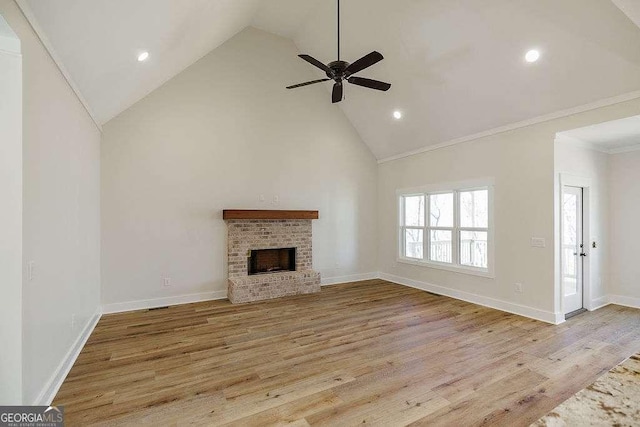 unfurnished living room with ornamental molding, a brick fireplace, wood finished floors, ceiling fan, and high vaulted ceiling