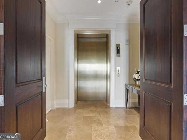 corridor featuring baseboards, ornamental molding, and elevator
