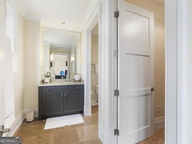 bathroom with toilet, baseboards, ornamental molding, and vanity