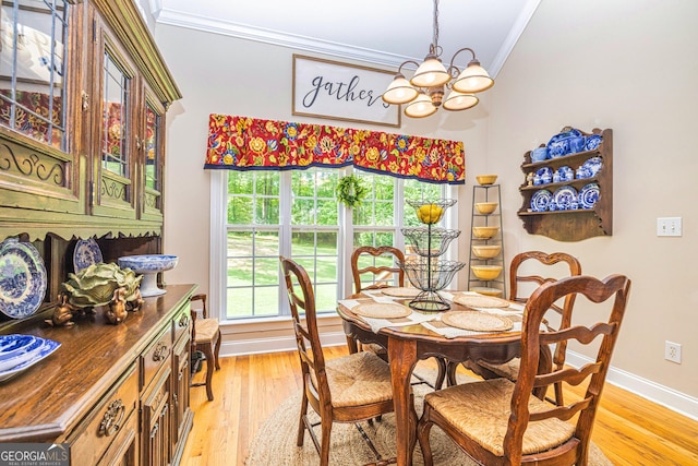 dining space with crown molding, a chandelier, light wood-type flooring, and baseboards