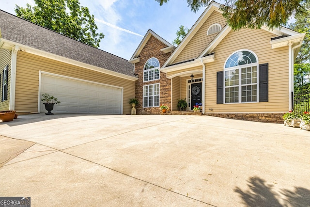 traditional home featuring driveway, a garage, and a shingled roof