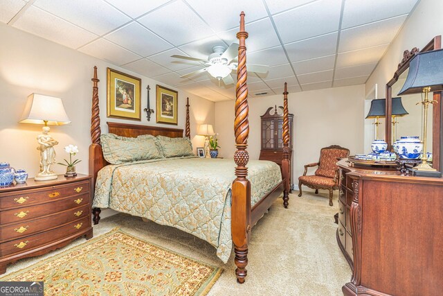 bedroom with light carpet, a drop ceiling, and a ceiling fan