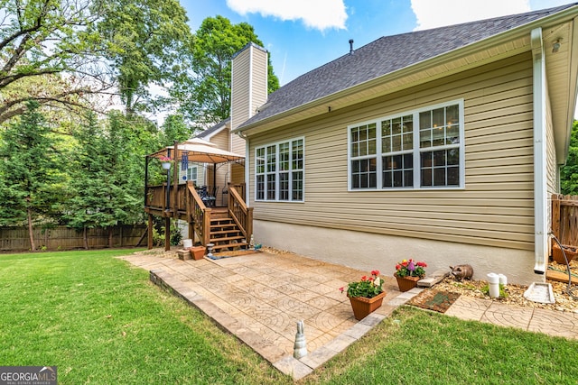 rear view of house with a gazebo, a chimney, a patio area, a shingled roof, and stairs