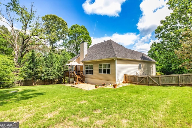back of property with a chimney, a shingled roof, a patio area, stairs, and a wooden deck