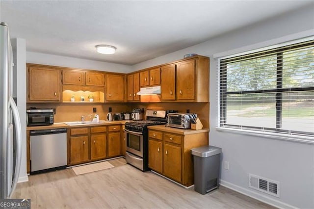 2469 Silver King Dr, Grayson, GA 30017 - kitchen featuring visible vents, under cabinet range hood, brown cabinets, a sink, and stainless steel appliances