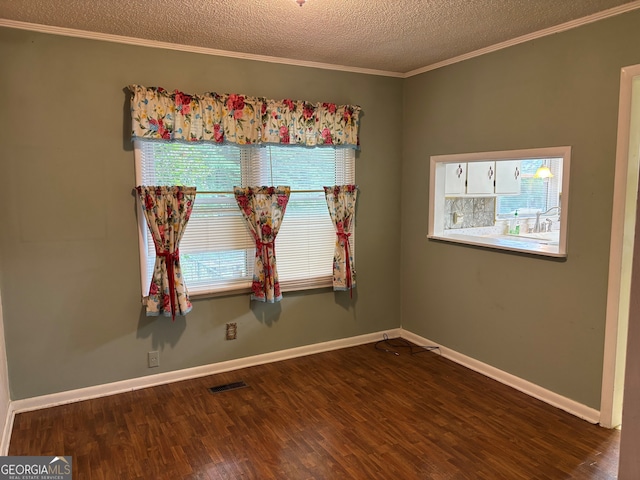 spare room with crown molding, visible vents, a healthy amount of sunlight, and wood finished floors
