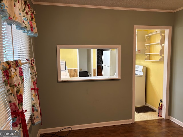 interior space with freestanding refrigerator, ornamental molding, wood finished floors, baseboards, and washer / clothes dryer