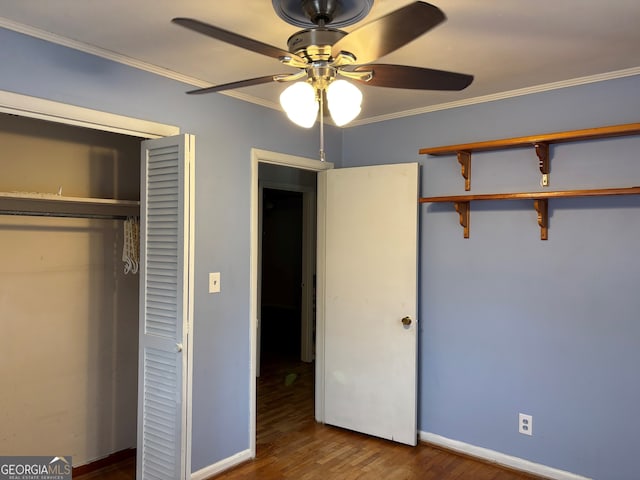 unfurnished bedroom featuring a closet, ornamental molding, wood finished floors, baseboards, and a ceiling fan