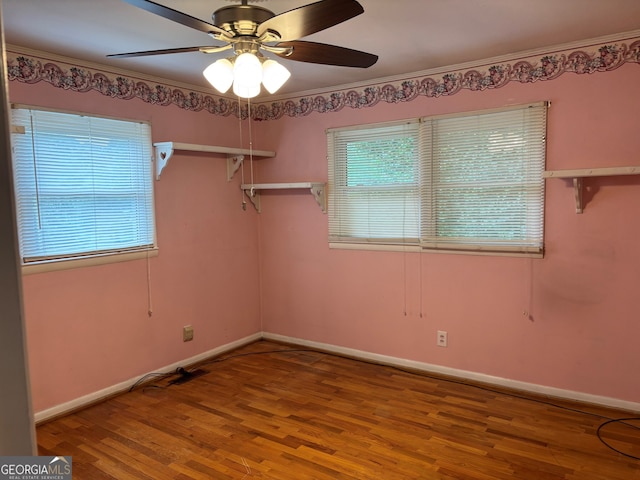 empty room with a ceiling fan, baseboards, ornamental molding, and wood finished floors