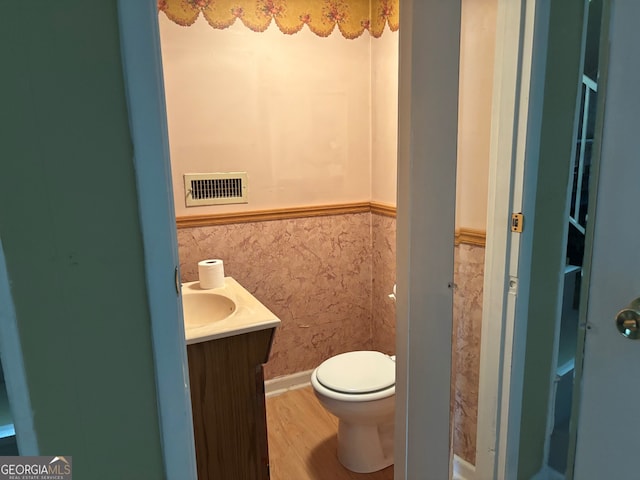 bathroom featuring visible vents, wainscoting, wood finished floors, toilet, and tile walls