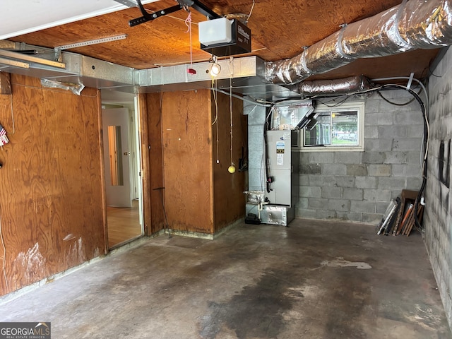 basement featuring concrete block wall and heating unit