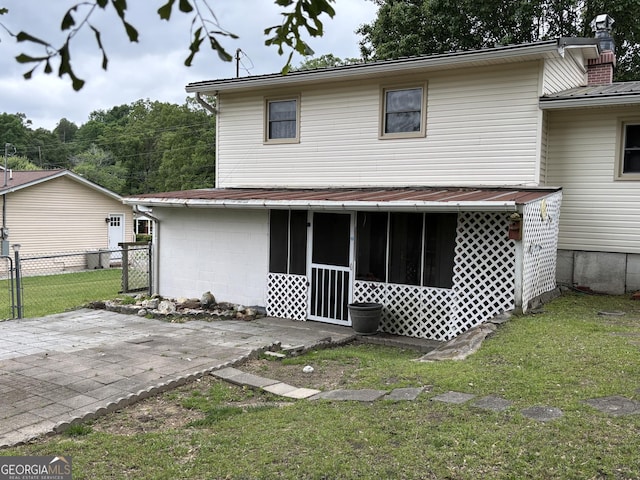 rear view of house featuring a lawn, a patio area, fence, and a sunroom