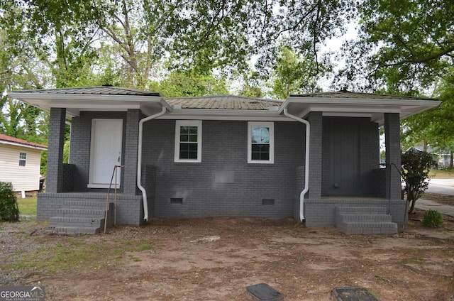 view of front of home with brick siding, metal roof, and crawl space