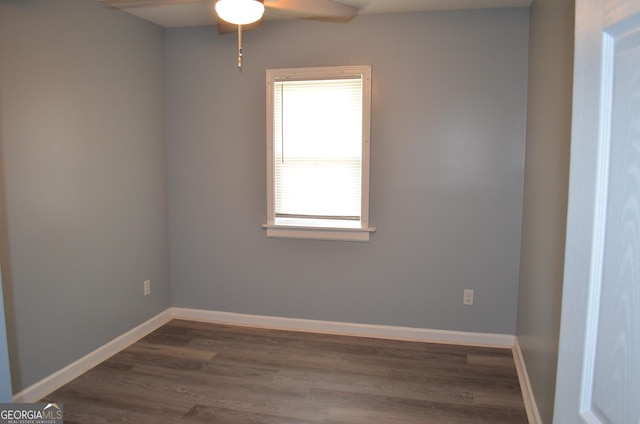empty room featuring dark wood-style flooring, a ceiling fan, and baseboards