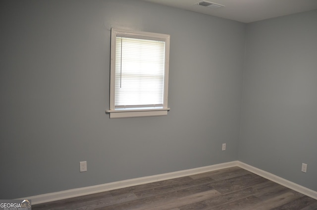 spare room featuring visible vents, baseboards, and dark wood-type flooring