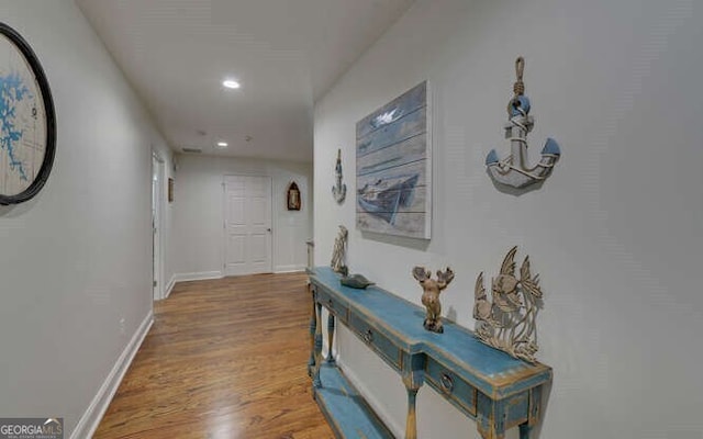 hallway featuring baseboards, recessed lighting, and wood finished floors