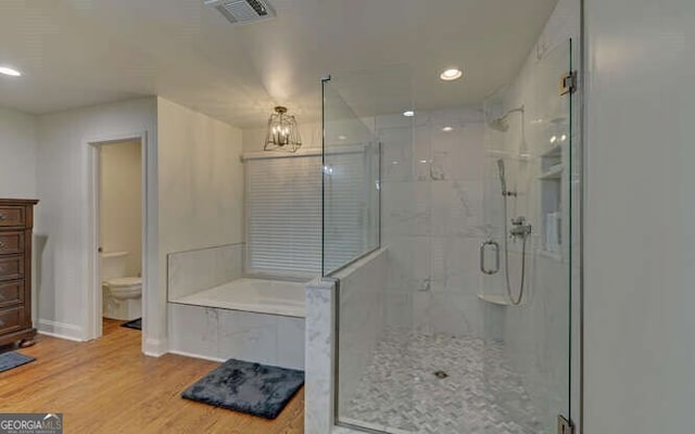bathroom featuring visible vents, wood finished floors, toilet, a bath, and a shower stall