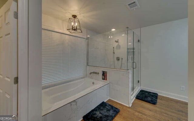 full bath featuring a notable chandelier, baseboards, wood finished floors, a bath, and a stall shower