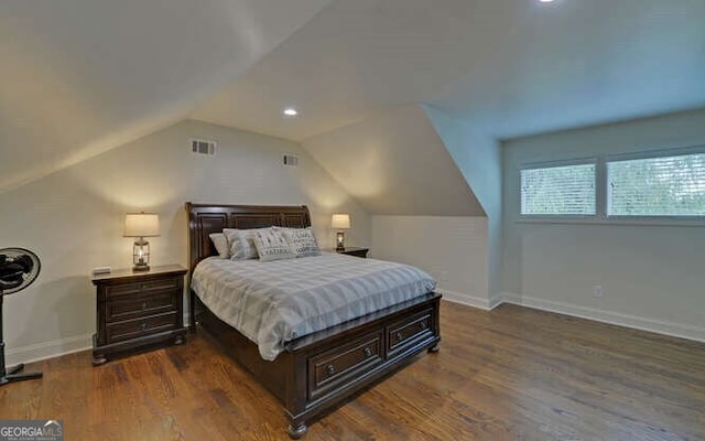 bedroom with visible vents, baseboards, wood finished floors, and vaulted ceiling