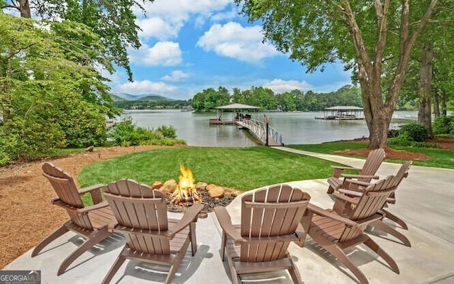 view of patio featuring a water view, an outdoor fire pit, and a dock