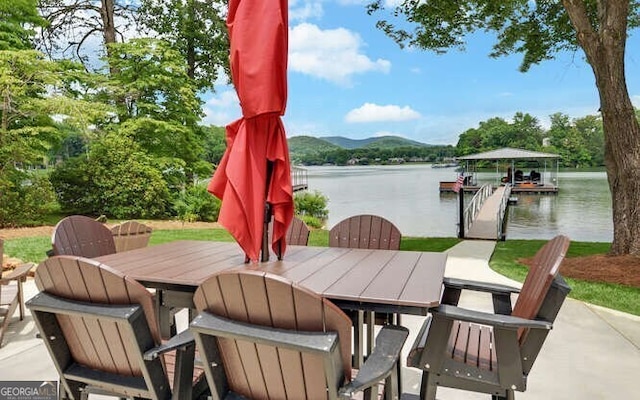 view of patio / terrace with outdoor dining area, a water view, and a boat dock