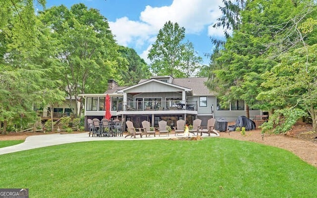 rear view of property featuring a yard, a patio, and a chimney