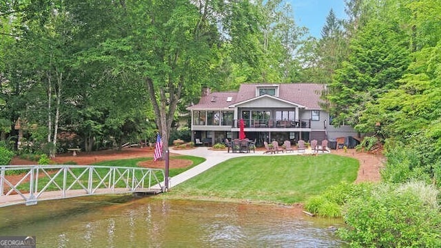 rear view of property featuring a water view, a patio area, and a yard