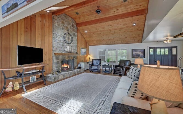 living room featuring a stone fireplace, wood walls, beam ceiling, wood finished floors, and high vaulted ceiling