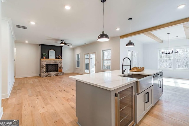 kitchen with pendant lighting, dishwasher, a sink, ceiling fan with notable chandelier, and beverage cooler