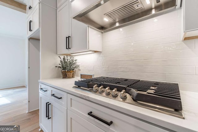 kitchen with white cabinetry, stainless steel gas cooktop, custom exhaust hood, and tasteful backsplash