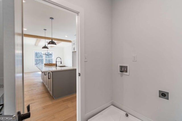 laundry area with baseboards, hookup for a washing machine, light wood-style floors, electric dryer hookup, and a sink