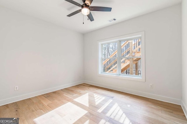 empty room featuring a ceiling fan, baseboards, visible vents, and light wood finished floors